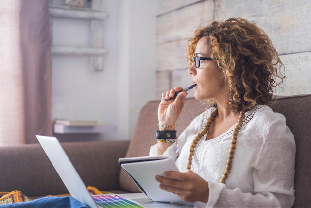 woman thinking whilst sat at laptop